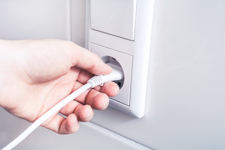 Pulling An Electrical Plug Out Of A Wall Socket, Energy Saving Concept