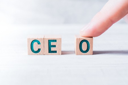 The Abbreviation CEO Formed By Wooden Blocks And Arranged By A Male Finger On A White Tableの写真素材