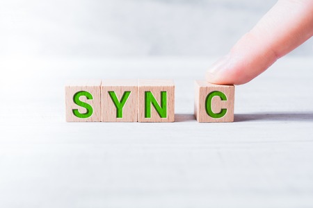 The Word Sync Formed By Wooden Blocks And Arranged By A Male Finger On A White Tableの写真素材