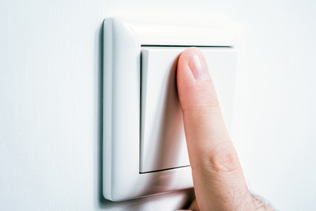 Male Finger Touching A Light Switch To Turn The Light On Or Offの写真素材
