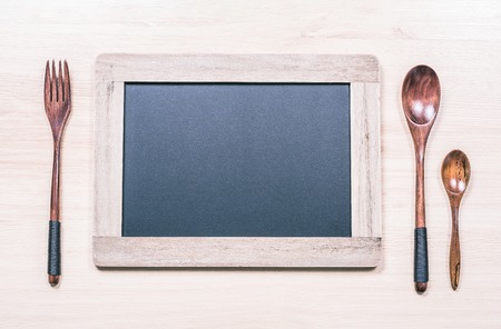 Blackboard With Wooden Frame And Copy Space For A Menu Next To A Wooden Fork And Two Spoonsの写真素材