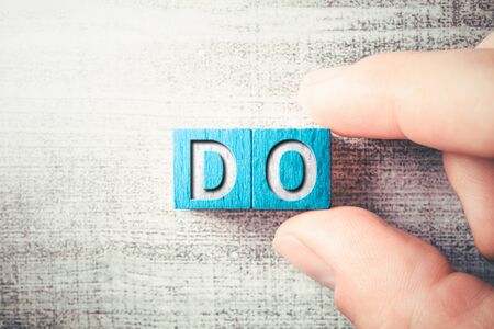 The Word DO On Wooden Blocks And Arranged By Two Male Fingers On A Tableの写真素材