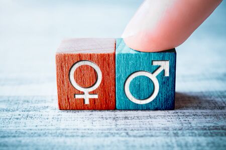 Gender Icon For Male On A Wooden Block Arranged By One Finger Next To The Female Sign On A Tableの写真素材