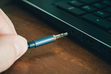 Hand Inserts Headphone Cable In Headphone Jack Of A Notebookの写真素材