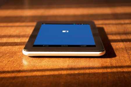 Tablet laying on the table with facebook page on the screenのeditorial素材