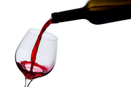 wine is poured into a glass on a white backgroundの写真素材