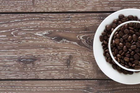 coffee beans in a white cup on a wooden backgroundの写真素材
