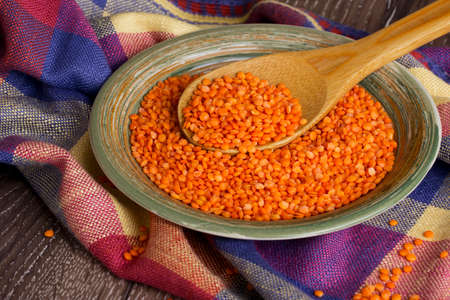 a handful of red lentils in a clay dishの写真素材