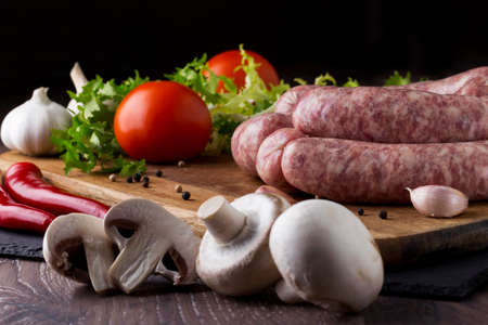 raw sausage and vegetables on a wooden tableの写真素材