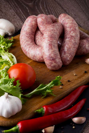 raw sausage and vegetables on a wooden tableの写真素材
