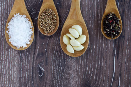 cloves of garlic and spices in wooden spoons