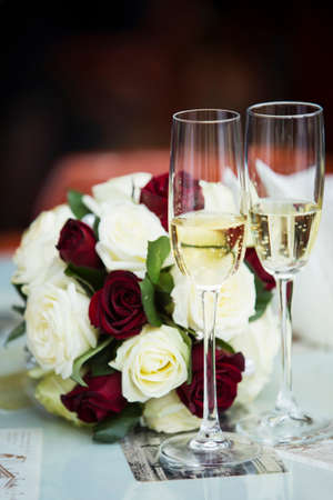 glass with champagne near a bouquet of rosesの写真素材