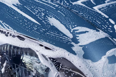 a blue car is washing in soap suds