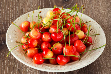 sweet cherry in a plate on wooden tableの写真素材