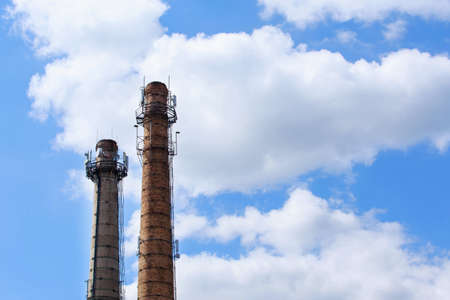 Industrial chimney against the sky with cloudsの写真素材