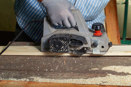 the carpenter is polishing a wooden board