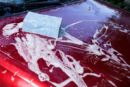 red car is washing in soap suds