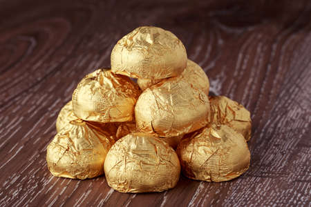 Candy in gold wrapper on the wooden background