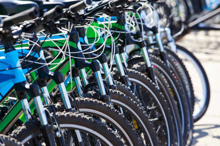 many bicycles stand in a row in the open airの写真素材