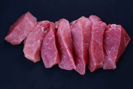 pieces of meat on a black cutting boardの写真素材