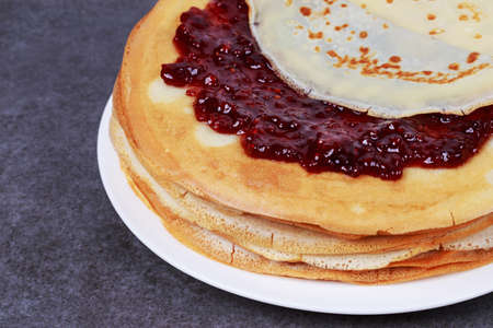 stack of pancakes with jam on a white plate