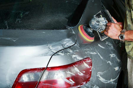 Young man polishes a gray car in the garage