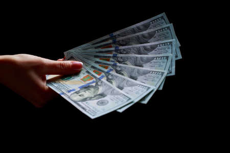 The hands with fan dollars over black background