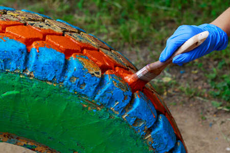 The process of painting an old car tire with a brushの写真素材
