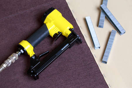 The pneumatic stapler lies on brown upholsteryの写真素材