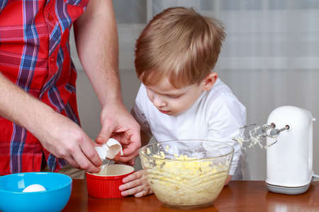 Dad and son make dough in the kitchen for pie