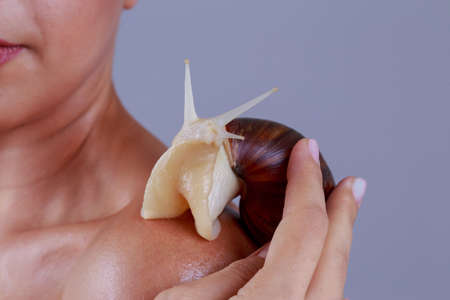 Young girl with big Achatina snail on a shoulderの写真素材