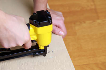 Restoring old sofa upholstery using a pneumatic staplerの写真素材