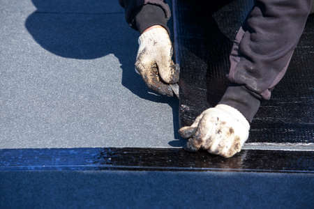 Worker cuts roofing material in the open air