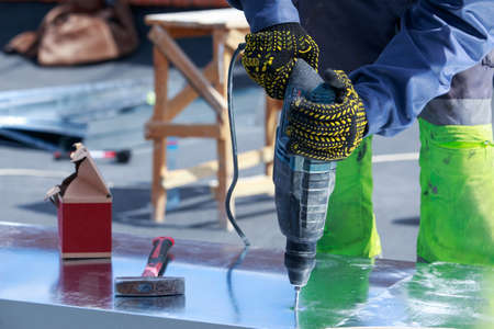 Worker with pneumatic hammer drill perforator equipment making hole
