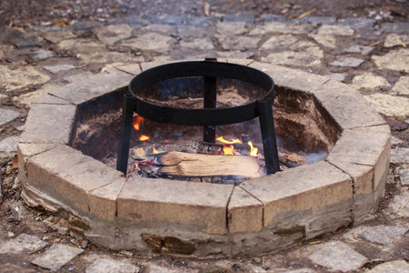 Chopped wooden logs in red and orange hot flames burning in firepit outside.