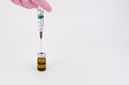 A gloved hand with a syringe and a vaccineの写真素材