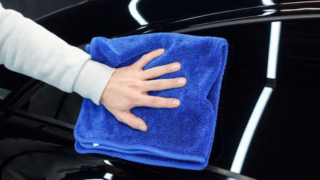 A man wipes a car with a rag