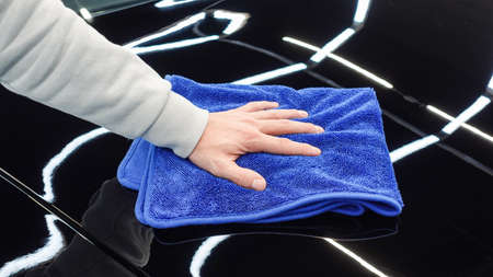 A man wipes a car with a rag