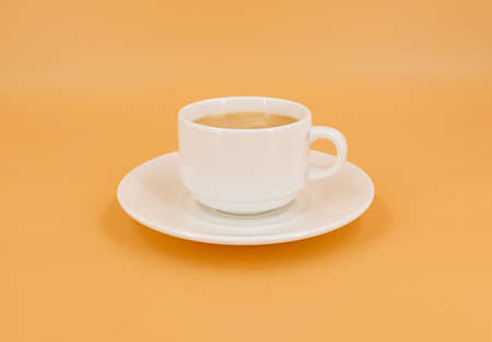 White cup with coffee on orange backgroundの写真素材