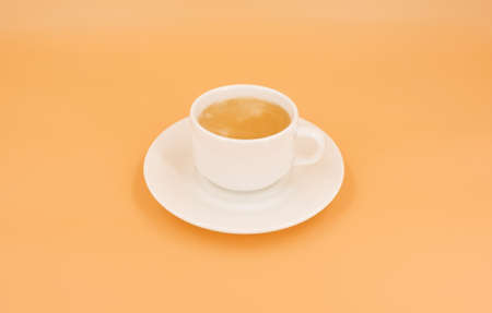 White cup with coffee on orange backgroundの写真素材