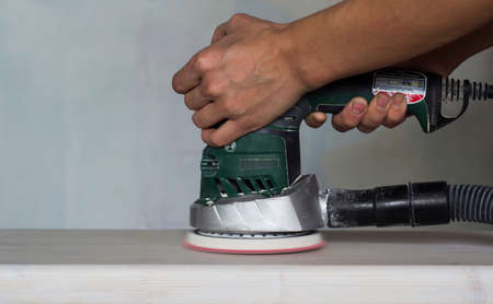 Polishing a white wooden board with an orbital grinder