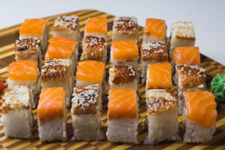 The set of rolls with ginger and wasabi on bamboo board. Unagi rolls and philadelphia rolls. Focus on middle line.の写真素材