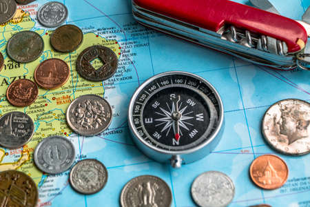 Many silver and golden coins and travel accessories  on travel map.