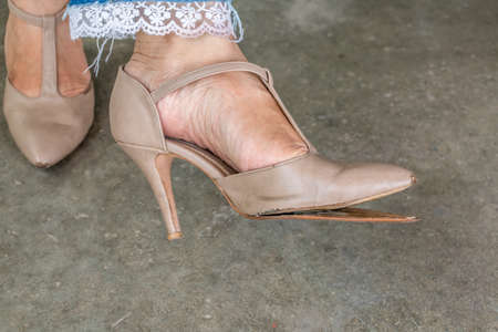 Female hand use broken high heel shoes on the floor.