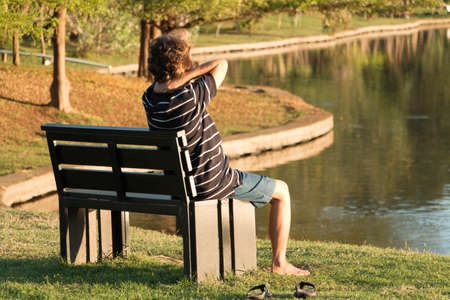 Man stress ware black and white shirt sit alone in the park at noon.