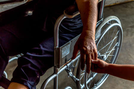 Person sit on wheelchair, Kid encourage to mom injured sit on wheelchair.の写真素材