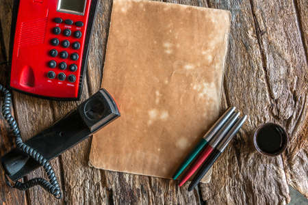 Old Black and Red telephone not use put on old brown wooden, Old paper and three fountain pen.の写真素材