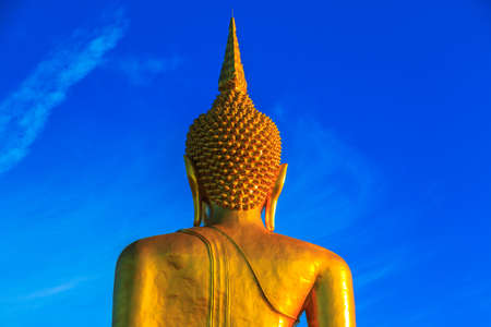 Golden large Buddha statue on temple for building, with clear blue sky.の写真素材