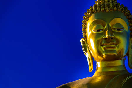 Golden large Buddha statue on temple for building, with clear blue sky.の写真素材