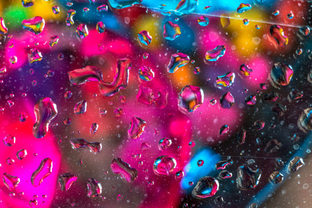 Reflections of a colored marbles in water droplets on glass.